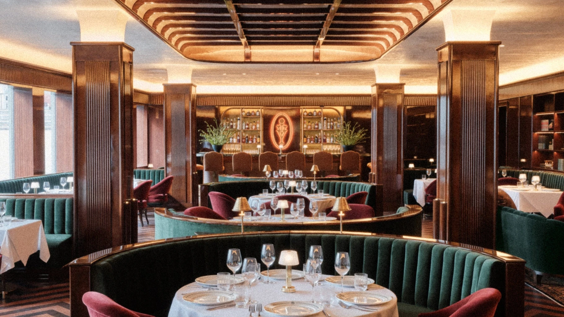 Kith Ivy dining room with green velvet booths, mahogany columns and the neon Ivy monogram bar